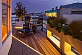 ZIGGURAT ROOF GARDEN BY AMIR SCHLEZINGER  MY LANDSCAPES: ROOF TERRACE LIT UP AT NIGHT WITH CHAIRS  TABLE  CONTAINERS PLANTED WITH BERGENIA CILIATA DUMBO  CAREX PRAIRIE FIRE