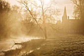 WELFORD PARK, BERKSHIRE: THE CHURCH AND RIVER AT DAWN WITH MIST RISING OFF THE WATER - FEBRUARY, WINTER, LANDSCAPE