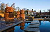 BROUGHTON GRANGE, OXFORDSHIRE: DESIGNER TOM STUART - SMITH: CLIPPED TOPIARY BEECH HEDGES IN FROST IN THE WALLED GARDEN. WINTER, COUNTRY GARDEN, POOL, POND, STEPPING STONES, WATER