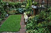 OVERVIEW OF SMALL TOWN GARDEN: URBAN OASIS. YORK STONE PATH RUNS AROUND CENTRAL LAWN SURROUNDED BY LUSH GREEN PLANTING AND BRICK WATER FEATURE. DESIGNER: ANTHONY NOEL