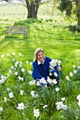 EASTON WALLED GARDEN  LINCOLNSHIRE: URSULA CHOLMELY IN THE MEADOW SURROUNDED BY NARCISSUS POETICUS RECURVUS - PHEASANTS EYE NARCISSUS - DAFFODILS  WHITE FLOWERS. SPRING.