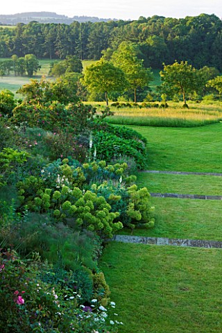 BROCKHAMPTON_COTTAGE_HEREFORDSHIRE_LAWN_AND_TERRACING_WITH_BORDER_OF_EUPHORBIAS_AND_VIEW_TO_COUNTRYS