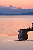 CORFU, GREECE - THE KASSIOPIA ESTATE: EVENING LIGHT - VIEW OUT TO SEA AT DUSK WITH STONE URN AND ALBANIAN MOUNTAINS IN THE DISTANCE.