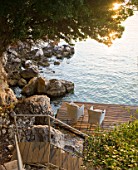 CORFU, GREECE - THE KASSIOPIA ESTATE: VIEW OF STEPS LEADING DOWN ONTO DECKED SEATING AREA IN THE BAY WITH VIEW OUT TO SEA. A PLACE TO SIT.