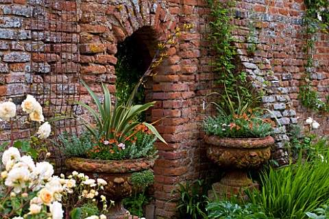 BIRTSMORTON_COURT_WORCESTERSHIRE_THE_WALLED_GARDEN__CONTAINERS_PLANTED_WITH_PHORMIUMS_BESIDE_DOORWAY