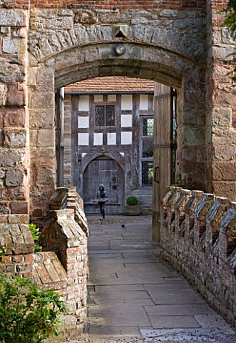 BIRTSMORTON_COURT_WORCESTERSHIRE_VIEW_THROUGH_ARCHWAY_ACROSS_THE_BRIDGE_TO_THE_COURTYARD_BESIDE_THE_