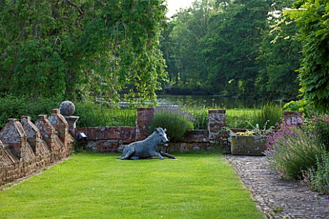 BIRTSMORTON_COURT_WORCESTERSHIRE_TERRACE_BESIDE_THE_HOUSE_WITH_LAWN_AND_SCULPTURE_OF_WILD_BOAR__SUMM