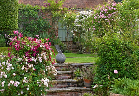 POULTON_HOUSE_GARDEN_WILTSHIRE_THE_WALLED_ROSE_GARDEN__BRICK_STEPS_LEADING_UP_TO_LAWN_WITH_ROSES__RO