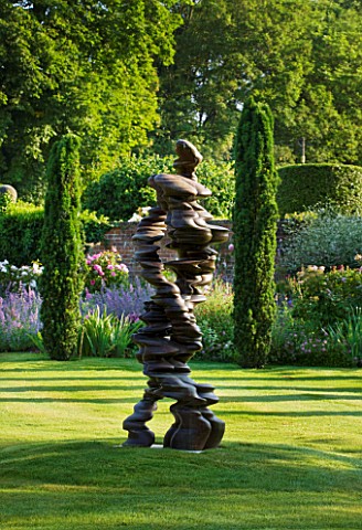 POULTON_HOUSE_GARDEN_WILTSHIRE_LAWN_WITH_IRISH_YEWS_AND_ABSTRACT_BRONZE_STATUE__SCULPTURE_CALLED_CHA