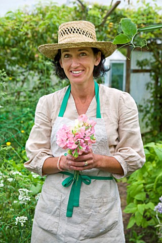 COMMON_FARM_FLOWERS_SOMERSET_SUMMER_LADY_WITH_HAT_HOLDING_BOUQUET_OF_SWEET_PEAS_IN_THE_GARDEN__FLOWE