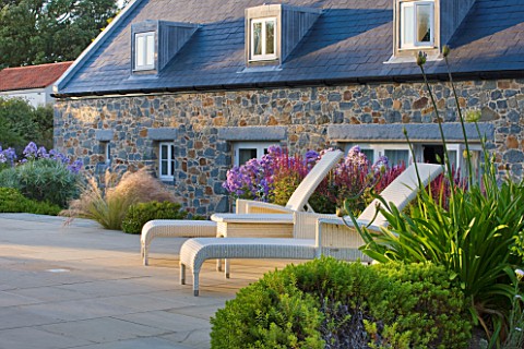 LE_HAUT_GUERNSEY_BORDER_BY_SWIMMING_POOL_WITH_DECK_CHAIRS_STIPA_TENUISSIMA_AND_CAMPANULA