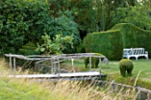 WOOLSTONE MILL HOUSE, OXFORDSHIRE: WOODEN BRIDGE OVER STREAM WITH YEW HEDGE AND BENCH. A PLACE TO SIT
