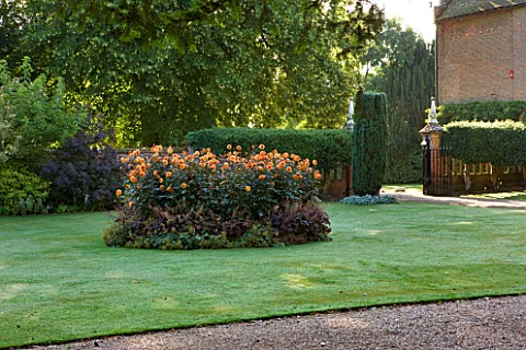 CHENIES_MANOR_BUCKINGHAMSHIRE_LAWN_AT_FRONT_OF_MANOR_HOUSE_WITH_BED_OF_DAHLIA_DAVID_HOWARD__COUNTRY_