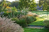 MARCHANTS HARDY PLANTS, EAST SUSSEX: LAWN AND HERBACEOUS BORDER OF PERENNIALS AND GRASSES. COUNTRY, GARDEN, ENGLISH, LATE SUMMER, AUTUMN