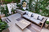 DESIGNER STEPHEN WOODHAMS, LONDON: ROOF GARDEN - RAISED BEDS, DECKING, SOFA, SEAT, SEATING, CUSHIONS, WOODEN TABLE, COTSWOLD STONE SCULPTURE BY TOM STOGDON. PATIO, TERRACE, FORMAL