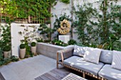 DESIGNER STEPHEN WOODHAMS, LONDON: ROOF GARDEN - RAISED BEDS, DECKING, SOFA, SEAT, SEATING, CUSHIONS, WOODEN TABLE, COTSWOLD STONE SCULPTURE BY TOM STOGDON. PATIO, TERRACE, FORMAL
