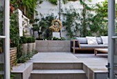 DESIGNER STEPHEN WOODHAMS, LONDON: ROOF GARDEN - RAISED BEDS, DECKING, SOFA, SEAT, SEATING, CUSHIONS, WOODEN TABLE, COTSWOLD STONE SCULPTURE BY TOM STOGDON. PATIO, TERRACE, STEPS