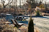 ELLICAR GARDENS, NOTTINGHAMSHIRE: FRSOTY LAWN WITH WOODEN SEATS AND BEEHIVE IN FROST. WINTER