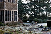 SEDGWICK PARK, WEST SUSSEX. PAVED TERRACE BESIDE HOUSE IN WINTER. FROST, GARDEN, JANUARY