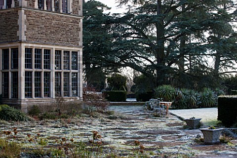 SEDGWICK_PARK_WEST_SUSSEX_PAVED_TERRACE_BESIDE_HOUSE_IN_WINTER_FROST_GARDEN_JANUARY