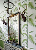 BUTTER WAKEFIELD HOUSE, LONDON. THE HALLWAY AT CHRISTMAS DECORATED WITH ANTIQUE MIRROR, ANTIQUE WOODEN DEER HEADS AND GLASS GLOBE LANTERN