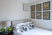 BUTTER WAKEFIELD HOUSE, LONDON. ZOES BEDROOM AT CHRISTMAS. NEUTRAL BACKDROP AND BED LINEN WITH VINTAGE WALL PRINTS AND PATTERNED CUSHIONS