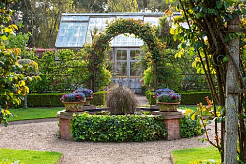 EAST_RUSTON_OLD_VICARAGE_GARDEN_NORFOLK_THE_GLASSHOUSE_GARDEN_WITH_ROUND_POOL__POND_IN_SPRING_AND_AR