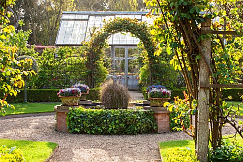 EAST_RUSTON_OLD_VICARAGE_GARDEN_NORFOLK_THE_GLASSHOUSE_GARDEN_WITH_ROUND_POOL__POND_IN_SPRING_AND_AR