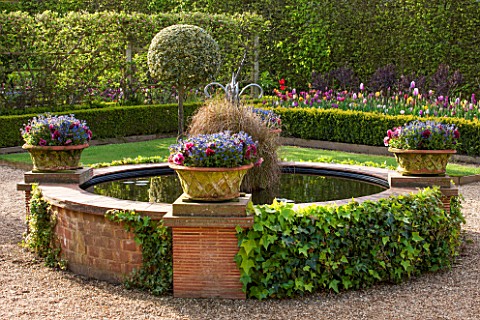 EAST_RUSTON_OLD_VICARAGE_GARDEN_NORFOLK_THE_GLASSHOUSE_GARDEN_WITH_ROUND_RAISED_POOL__POND_IN_SPRING