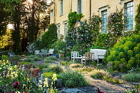 ABLINGTON_MANOR__GLOUCESTERSHIRE_TERRACE_IN_FRONT_OF_MANOR_HOUSE_WITH_WOODEN_TABLE_AND_CHAIRS__IRIS_