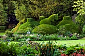 ABLINGTON MANOR  GLOUCESTERSHIRE: VIEW ACROSS LAWN TO CLIPPED TOPIARY YEW. CLASSIC COUNTRY GARDEN  JUNE  SUMMER  ROMANCE  ROMANTIC