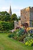 BROUGHTON CASTLE, OXFORDSHIRE: THE BATTLEMENT BORDER IN SUMMER WITH CARDOONS AND BLUE DELPHINIUMS - FLOWERS, SUMMER, JUNE, HERBACEOUS BORDER, GARDEN