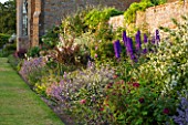 BROUGHTON CASTLE, OXFORDSHIRE: BORDER BESIDE THE WALLED GARDEN PLANTED WITH NEPETA AND DELPHINIUMS - FLOWERS, SUMMER, JUNE, HERBACEOUS BORDER, GARDEN