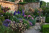 BROUGHTON CASTLE, OXFORDSHIRE: BORDER WITH WOODEN BENCH / SEAT, ROSES, OENOTHERA AND DELPHINIUMS - FLOWERS, SUMMER, JUNE, HERBACEOUS BORDER, GARDEN, GRAVEL, A PLACE TO SIT