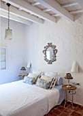 CIUTADELLA MENORCA, SPAIN: EVELYNE MANDEL HOUSE - CLASSIC BEDROOM IN WHITE - BED, BLUE AND WHITE CUSHIONS, ANTIQUE FRENCH WOODEN MIRROR, LAMPS AND BEDSIDE TABLES
