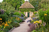 WEST DEAN GARDENS, WEST SUSSEX: LATE SUMMER BORDERS PLANTED WIN YELLOW AND BLUE - PATH TO SUNDIAL - HERBACEOUS BORDER, FLOWERBEDS, FLOWER, BED. RUDBECKIA, AGAPANTHUS, HEMEROCALLIS
