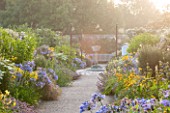 WEST DEAN GARDENS, WEST SUSSEX: LATE SUMMER BORDERS PLANTED IN YELLOW AND BLUE - PATH TO SUNDIAL - HERBACEOUS BORDER, FLOWERBEDS, FLOWER - AGAPANTHUS, PHLOMIS, HEMEROCALLIS
