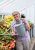 WEST DEAN GARDENS, WEST SUSSEX: SARAH WAIN WATERING INTHE GLASSHOUSE