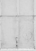 WEST DEAN GARDENS, WEST SUSSEX: BLACK AND WHITE IMAGE IN WINDOW WITH HEART IN ONE OF THE GREENHOUSES / GLASSHOUSES IN THE WALLED KITCHEN GARDEN. AUGUST