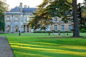 LAMPORT HALL, NORTHAMPTONSHIRE: HUGE CEDAR TREE IN FRONT OF THE HALL WITH ITALIAN GARDEN BEHIND, EVENING LIGHT. HISTORIC HOUSE, CLASSIC, AUGUST