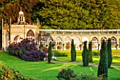 SEZINCOTE, GLOUCESTERSHIRE: THE MAGNIFICENT CURVING ORANGERY WITH CONTAINERS OF FUCHSIAS OUTSIDE IN MORNING LIGHT - IRISH YEWS