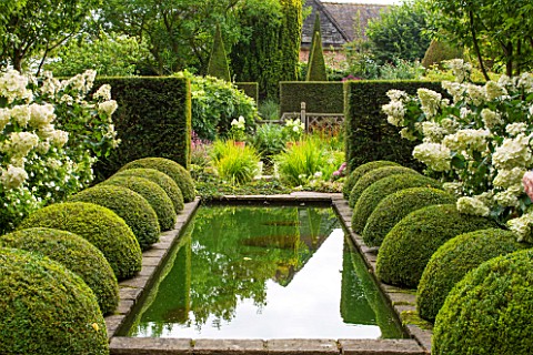 WOLLERTON_OLD_HALL_SHROPSHIRE_THE_RILL_GARDEN_WITH_CANAL_CLIPPED_BOX_HYDRANGEAS_IN_CONTAINERS_STANDA