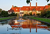 RHS GARDEN, WISLEY, SURREY: THE HOUSE AND LABORATORY AT SUNSET SEEN ACROSS THE CANAL FROM THE LOGGIA, WATER, FOUNTAIN, SEPTEMBER, SUMMER, GARDEN, CLASSIC