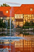 RHS GARDEN, WISLEY, SURREY: THE HOUSE AND LABORATORY AT SUNSET SEEN ACROSS THE CANAL FROM THE LOGGIA, WATER, FOUNTAIN, SEPTEMBER, SUMMER, GARDEN, CLASSIC