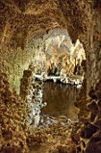 PAINSHILL PARK, SURREY: THE CRYSTAL GROTTO - VIEW THROUGH WINDOW OPENING TO LAKE AND REFLECTIONS - CLASSIC, OOLITIC LIMESTONE, STALACTITES, MYSTERY, LANDSCAPE GARDEN, ORNAMENT