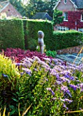 SURREY GARDEN DESIGNED BY ANTHONY PAUL: VIEW TO HOUSE WITH ASTERS AND SEDUMS AND FOCAL POINT OF POLISHED STONE SCULPTURE BY PAUL VANSTONE - SUMMER, SEPTEMBER, COUNTRY GARDEN