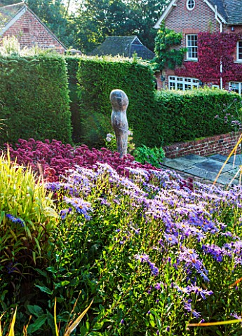 SURREY_GARDEN_DESIGNED_BY_ANTHONY_PAUL_VIEW_TO_HOUSE_WITH_ASTERS_AND_SEDUMS_AND_FOCAL_POINT_OF_POLIS