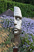 SURREY GARDEN DESIGNED BY ANTHONY PAUL: FOCAL POINT - PIXELATED STYLE STEEL HEAD BY RICK KIRBY WITH STIPA GIGANTEA AND ASTERS BEHIND - SUMMER, SEPTEMBER, COUNTRY GARDEN