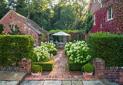 SURREY_GARDEN_DESIGNED_BY_ANTHONY_PAUL_VIEW_TO_BRICK_TERRACE_WITH_BEDS_OF_WHITE_HYDRANGEA_ANNABELLE_