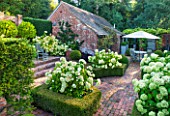 SURREY GARDEN DESIGNED BY ANTHONY PAUL: VIEW TO BRICK TERRACE WITH BEDS OF WHITE HYDRANGEA ANNABELLE - PATIO, SUMMER, COUNTRY GARDEN, FORMAL, SEPTEMBER